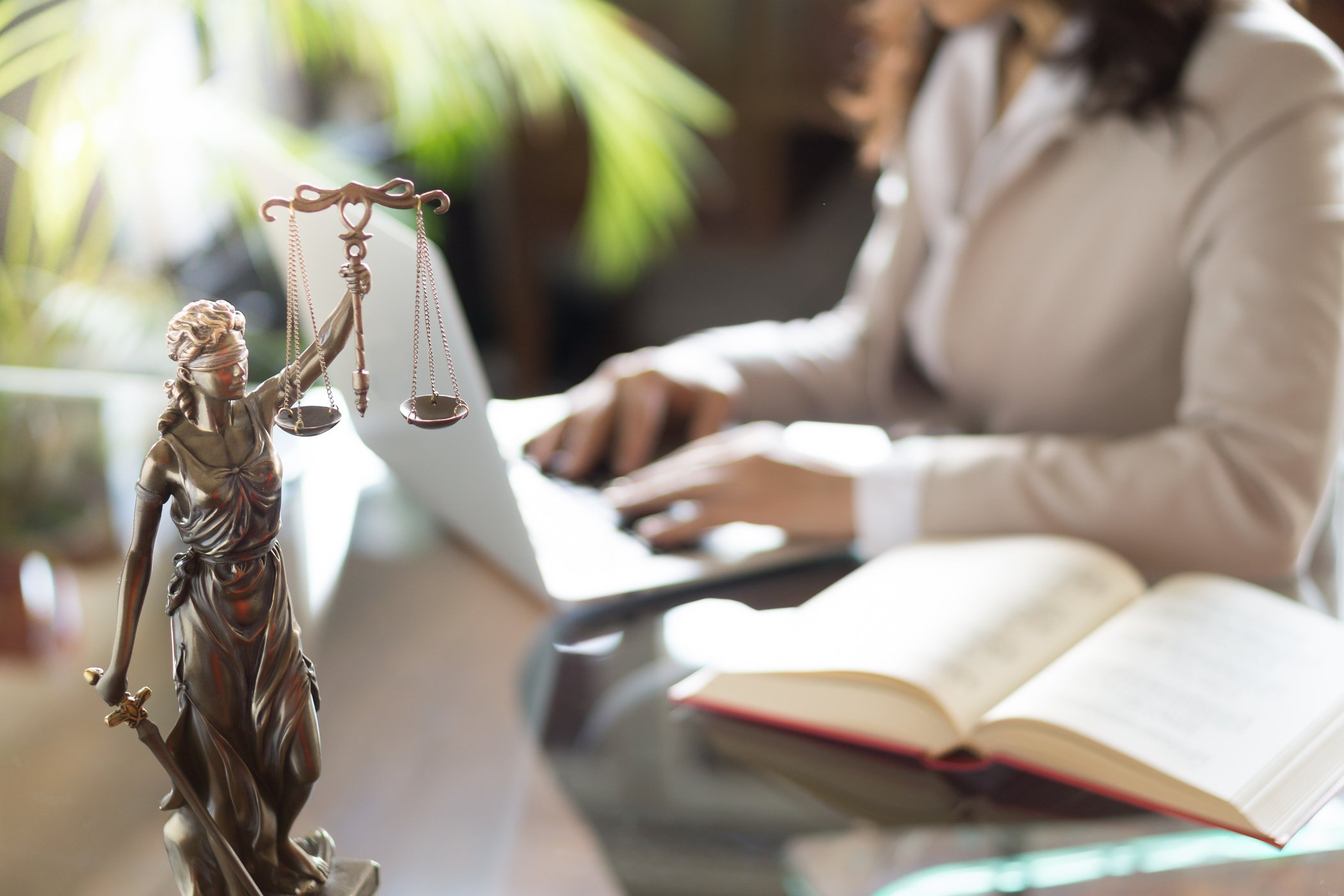 Lawyer office. Statue of Justice with scales and lawyer working on a laptop. Legal law, advice and justice concept